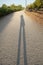 Shadow of an adult man in the summer sunshine on a pathway in nature. Early morning sunrise