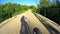 Shadow of cyclist cycling along dirt road through bridge in Bieszczady mountains on sunny day, Poland