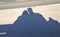 Shadow on the grey concrete of two people sitting on a bench