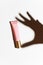 Shadow hands with a pink tube of moisturizing scream on a white background. The attribute of facial and hand care. Tonal,