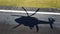 Shadow of helicopter flying over the grass and asphalt