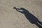 Shadow of man doing handcuffed sign on sand background.