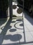 Shadow of metal fence gate on concrete tiles.