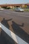 A shadow on the road of Travel hikers couple showing thumbs up on street for hitchhiking during road trip. Happy young