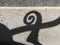 Shadow of a spiral, part of a handrail, on a stone wall