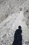 Shadow on the trail of the hiker with hat and a young woman walking in the mountains