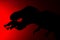 Shadow of tyrannosaurus biting a smaller dinosaur with red light