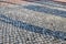 Shadows of people in a shopping area on a cobblestone ground