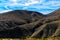 Shadows of ravines on barren desert mountains under a blue sky with white clouds