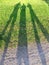 Shadows of three person on the green grass lawn