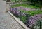 Shady corner behind the house by a road of granite cubes. metal ventilation grilles in the tiles resemble a carpet or doormat. whi