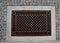 Shady corner behind the house by a road of granite cubes. metal ventilation grilles in the tiles resemble a carpet or doormat. whi