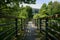 Shady fenced and planked footbridge to building in woods on sunny summer day