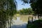 Shady fenced river bank in city of sunny summer afternoon