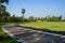 Shady footpath around grassy circular playground in sunny summer