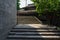 Shady stone stairway between stone wall and tile-roofed house in