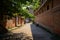 Shady street on slope between aged red-brick buildings in sunny