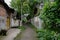 Shady unpaved alley between Chinese ancient houses in summer green