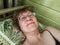 A shaggy, funny middle-aged woman in glasses takes a selfie on her smartphone in the bed in early morning. A blogger