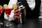 A shaker on a bar counter, a margarita glass full of cocktail, a hand of a bartender on a black blurred background.