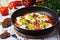 Shakshouka with five cooked eggs on top of tomato sauce in cast iron skillet