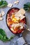 Shakshouka - Middle eastern traditional dish with poached eggs in tomato sauce, grey background