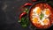 Shakshuka eggs in a pan on a black concrete background.