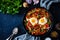 Shakshuka - fried eggs with vegetables on black wooden table, top view