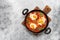 Shakshuka in a frying pan on a gray rustic background. Poached eggs in a spicy tomato pepper sauce. Typical Jewish or