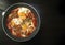 Shakshuka - poached eggs in tomato sauce, onion, pepper and spices in iron pan on dark wooden table with copy space