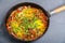Shakshuka sprinkled with green onions in a frying pan on a gray background