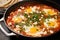 shakshuka topped with feta cheese in a stainless-steel pan