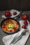 Shakshuka traditional middle eastern dish with tomatoes and eggs in a small pan garnished with scallions and chilli.