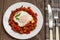 Shakshuka on a white plate. Traditional Jewish dish. Wooden table. Close-up