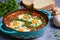 shakshuka in a white porcelain dish on a turquoise tablecloth