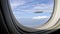 Shaky handheld video of airplane wing through porthole, blue sky with clouds. View of passenger on airplane flight in