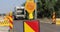 Shallow depth of field footage with road warning lights on a construction site and a garbage truck passing by.