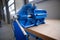 Shallow depth of field image with a heavy iron vice on a workbench inside a workshop with no people around