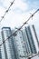 Shallow depth of field, old bared steel wire against blue sky with blurred modern buildings