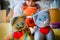 Shallow depth of field of three knitted stuffed toy cats with red hearts, woman sitting in the background.