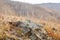 Shallow depth of field view of rock stones covered with lichen surrounded by yellow autumn grass on gentle hills