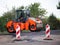 Shallow DOF road works restraints. Unfocused reflective paint sign. Heavy Vibration roller compactor at road