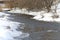 Shallow, fast, unfrozen river in winter. Snow melts spring streams