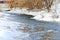 Shallow, fast, unfrozen river in winter. Snow melts spring streams