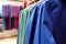 Shallow focus close up of a rack of blue and green clothes in a