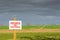 Shallow focus of a Private, No Footpath sign at the edge of a farmers crop field.