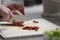 Shallow focus shot of a person cutting dried tomatoes with a knife on a white board