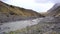 A shallow mountain river flows against a mountain with yellow grass in Iceland.