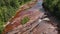 Shallow river with red rocks in the woods.