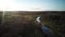 A Shallow River Surrounded By The Autumnal Plants On The Meadow aerial drone shot